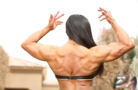Female bodybuilder Marina Lopez poses in the nude on back lawn
