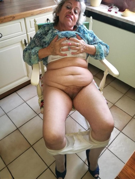 Horny granny Caro sticks a banana inside her natural pussy on kitchen chair