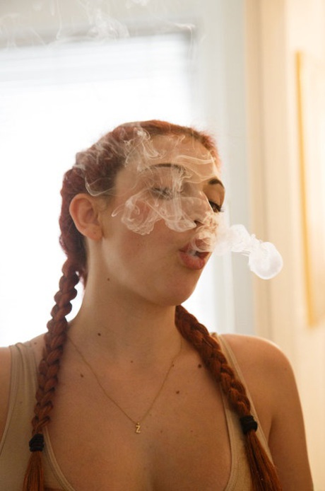 Redhead teen Gina Rosini smokes and shows her big breasts indoors